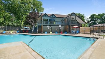 A large swimming pool in front of a two-story house.